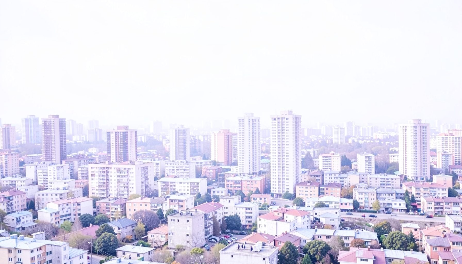 Yüksek binaların gerisine uzanan geniş bir kentsel dönüşüm sahası, soğuk gri ve beyaz ışıkta sabah manzarası